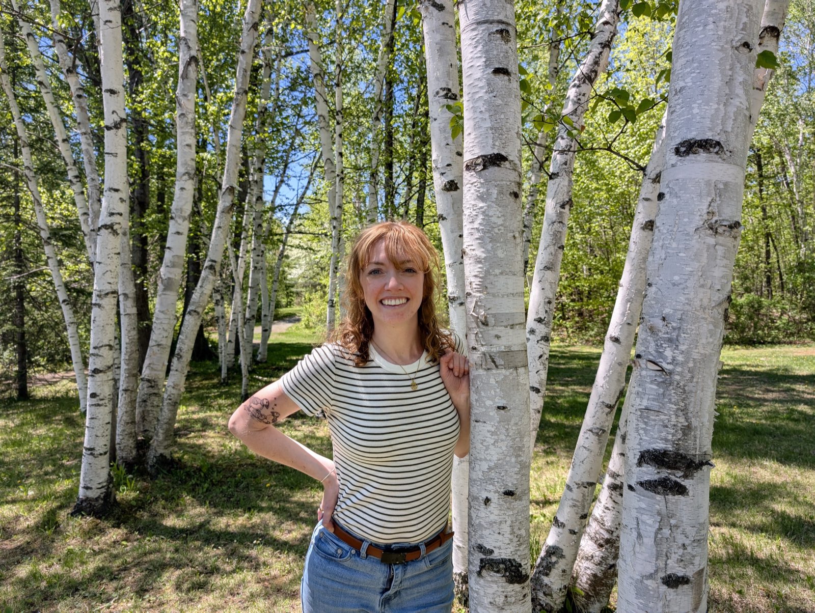 Britt, founder of moss + method, standing among birch trees in New Hampshire